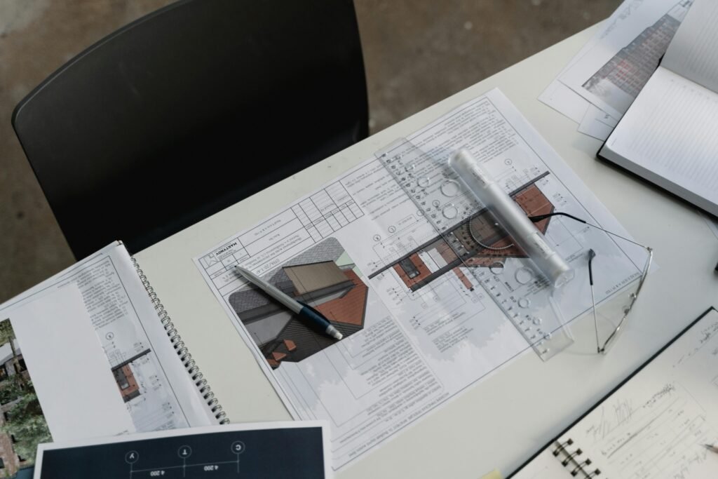 Top view of architectural blueprints and drafting tools on a workspace desk.